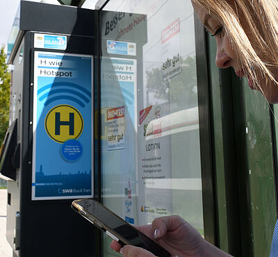 Frau steht an Haltestelle