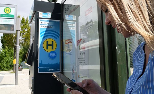 Frau steht an Haltestelle
