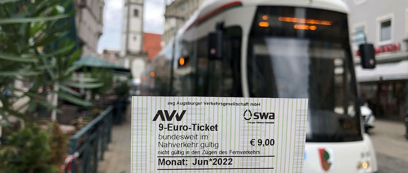 Foto eines AVV/swa 9-Euro-Tickets, im Hintergrund ist eine swa Tram zu sehen.
