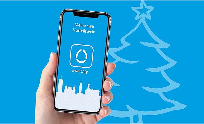 Eine Hand hält ein Smartphone, auf dessen Display die App "swa City" abgebildet ist. Im blauen Hintergrund befindet sich ein Christbaum.