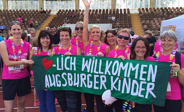 Teilnehmerinnen des Frauenlaufs stehen nebeneinander und halten ein Banner mit der Aufschrift 