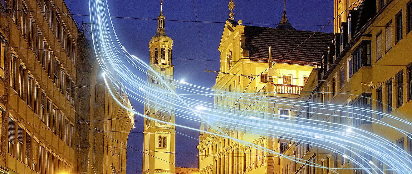 Augsburger Moritzplatz mit dem Perlachturm im Hintergrund und einem Lichteffekt im Vordergrund