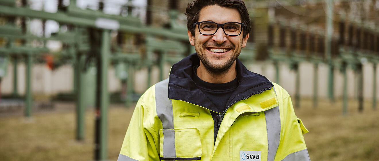 Mann mit swa Netze Schutzkleidung steht vor einer Netzeanlage