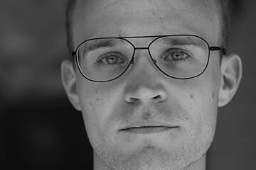 Portrait eines jungen Mannes mit Brille in Schwarz-Weiß-Optik. - Ein Klick auf das Bild führt zur vergrößerten Fotoansicht.