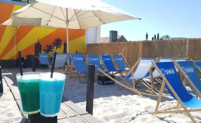 Getränke auf einem Tisch im Sonnendeck. Im Hintergrund sind Liegen mit swa Logo. 