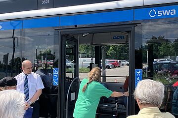 Frau steigt mit Rollator in Bus ein