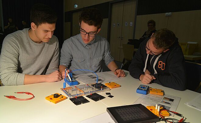 Schüler, die an der praxisorientierten Unterrichtseinheit der swa teilnehmen. Sie verwenden Experimentierkästen, um Schaltungen mit Komponenten wie Solarmodulen und Kabeln zu bauen und zu testen.