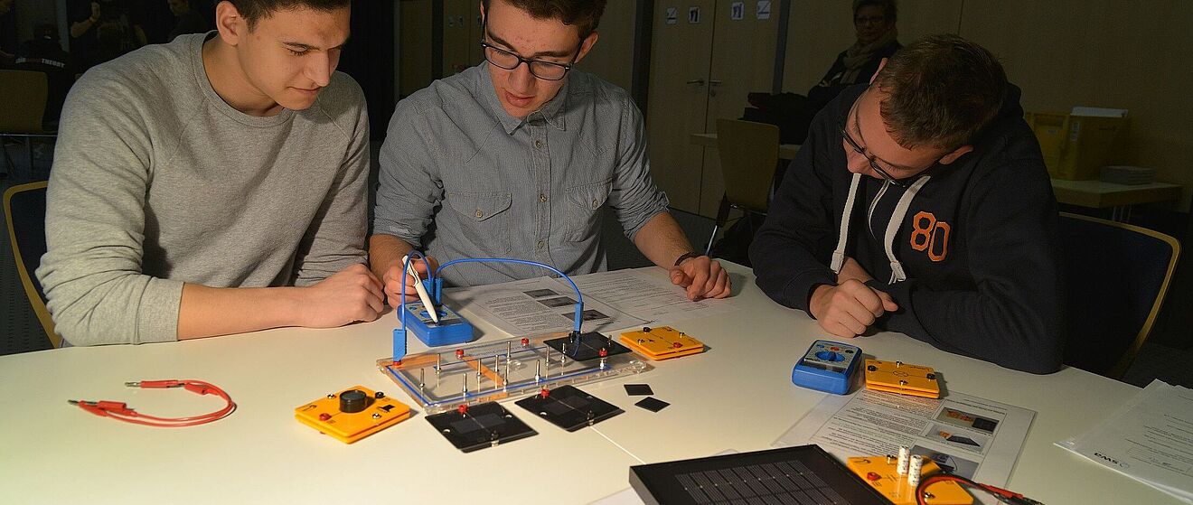 Schüler, die an der praxisorientierten Unterrichtseinheit der swa teilnehmen. Sie verwenden Experimentierkästen, um Schaltungen mit Komponenten wie Solarmodulen und Kabeln zu bauen und zu testen.