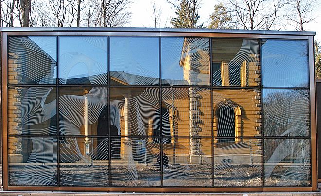 Modernes Glasgebäude spiegelt das historisches Wasserwerk am Hochablass in Augsburg.