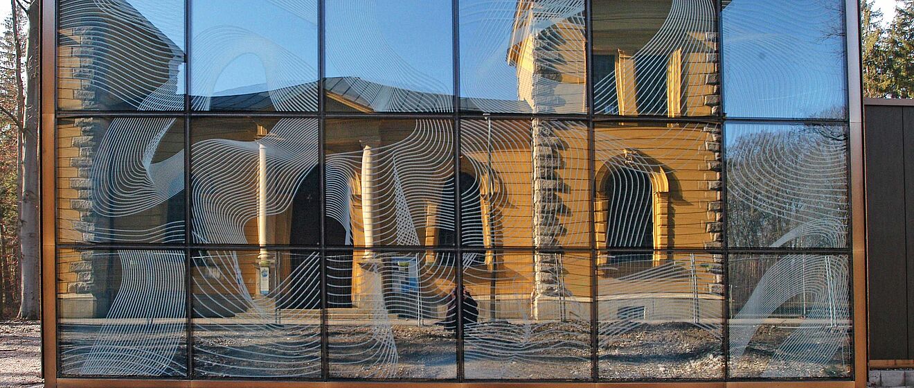 Modernes Glasgebäude spiegelt das historisches Wasserwerk am Hochablass in Augsburg.