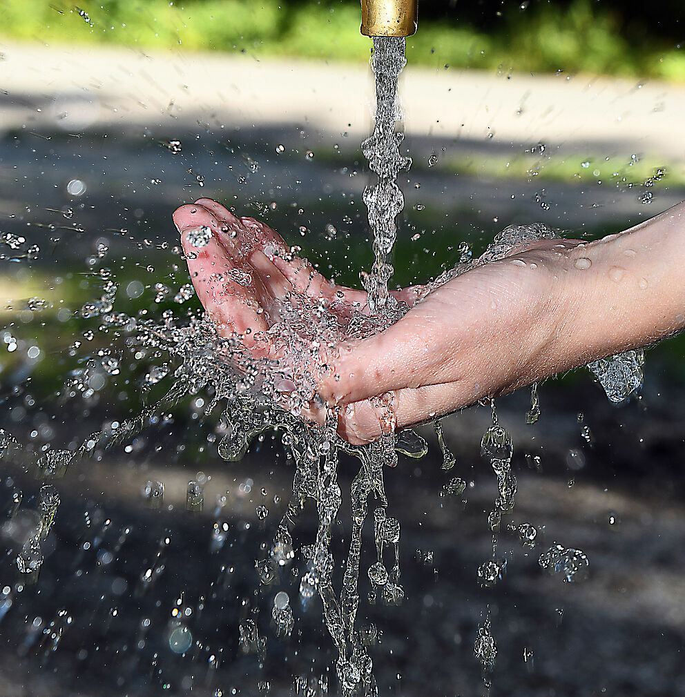 Wasserstrahl aus einem Wasserhahn fließt auf eine geöffnete Hand