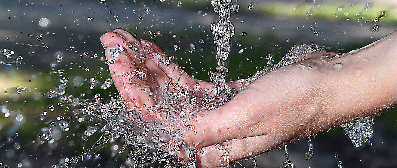 Wasserstrahl aus einem Wasserhahn fließt auf eine geöffnete Hand