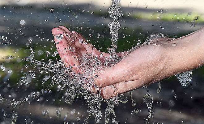 Wasserstrahl aus einem Wasserhahn fließt auf eine geöffnete Hand