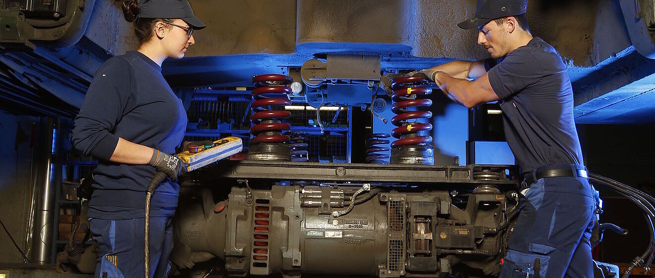 Zwei swa-Mitarbeiter stehen unter einem Auto in der Werkstatt