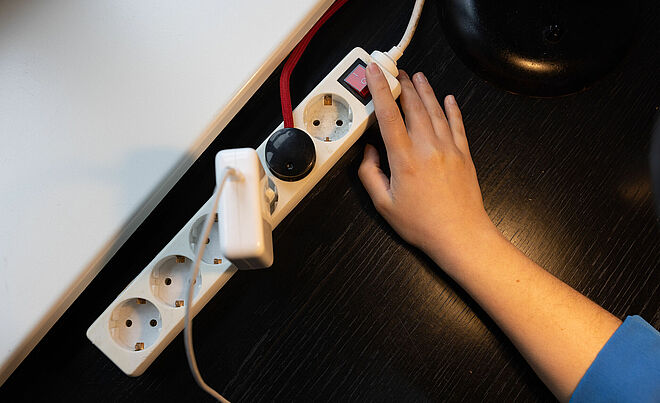 Hand betätigt Standby-Knopf einer Mehrfachsteckdose