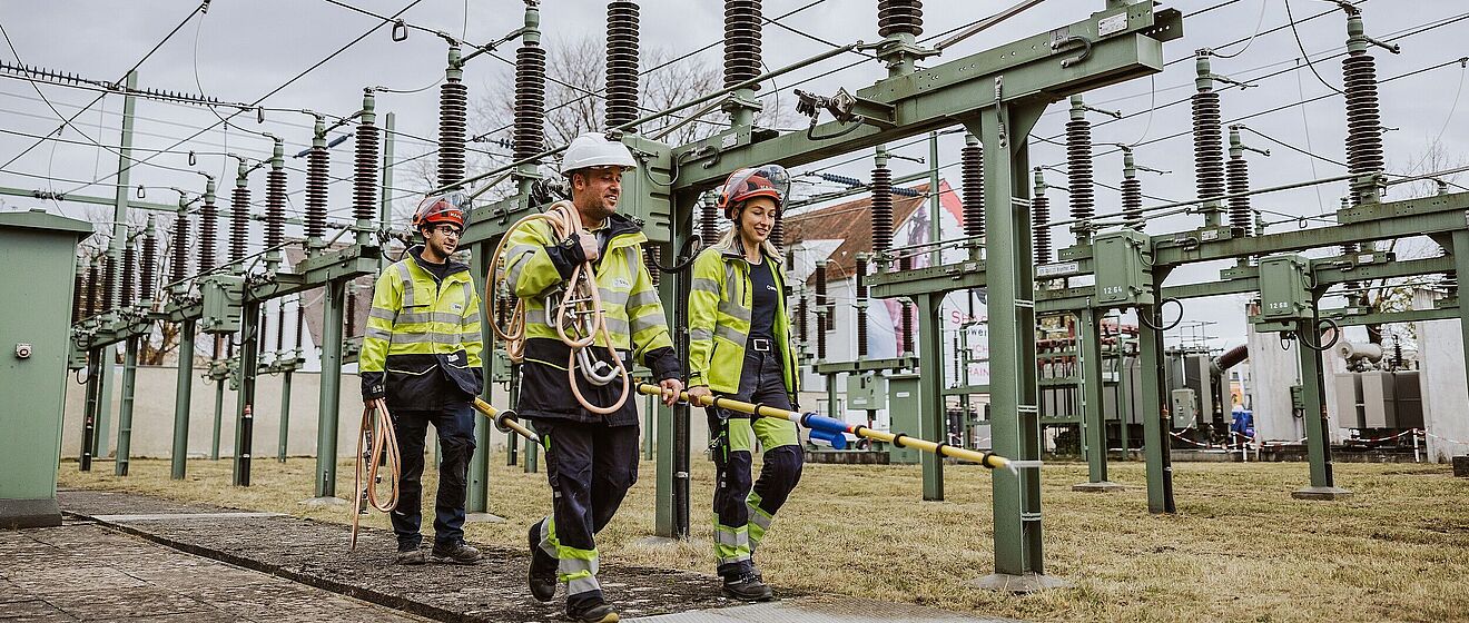 Drei swa Netze Mitarbeiter mit Ausrüstung laufen im Spannwerk.