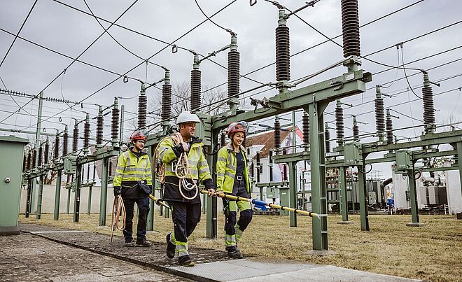 Drei swa Netze Mitarbeiter mit Ausrüstung laufen im Spannwerk.