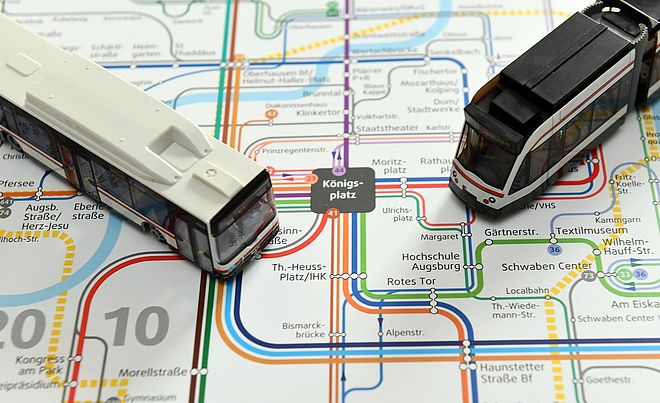 Modellbus und Modelltram auf einem Liniennetzplan Augsburgs.