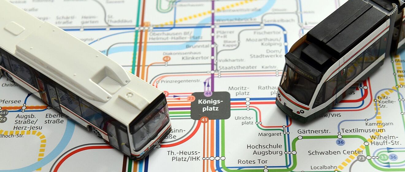 Modellbus und Modelltram auf einem Liniennetzplan Augsburgs.