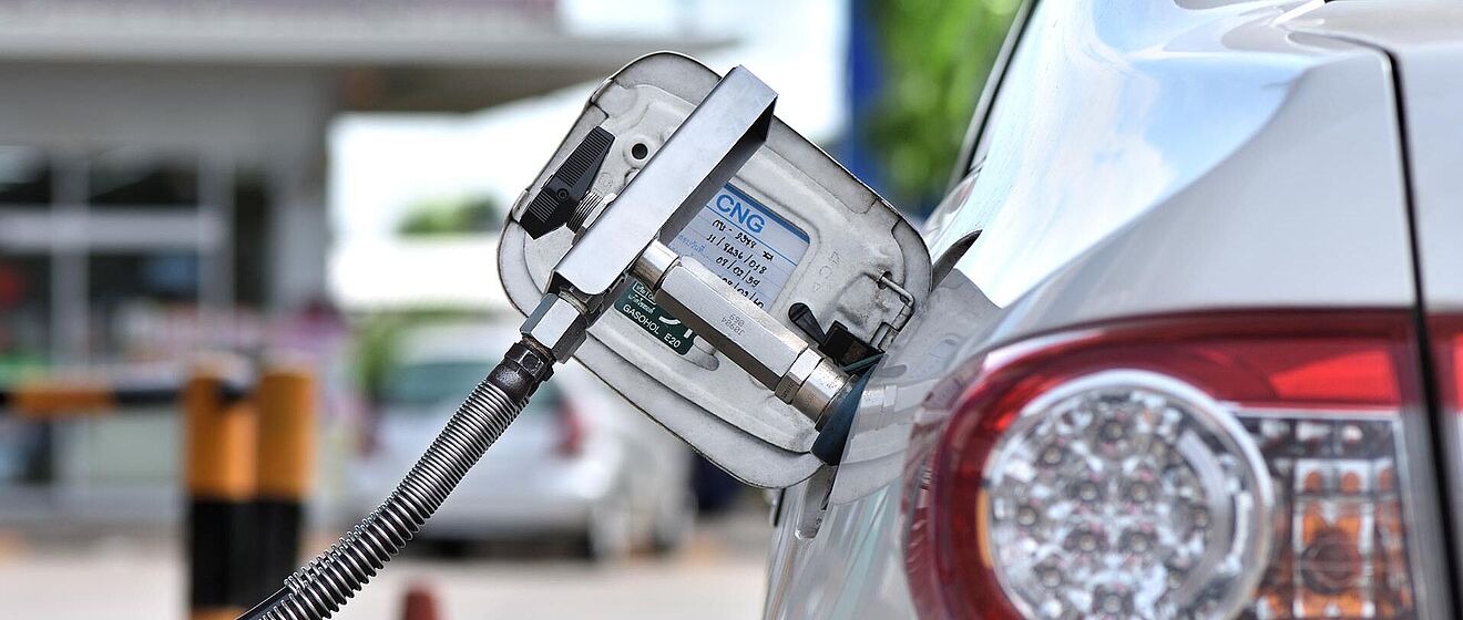 Tankstellenschlauch steckt in einem Auto mit Erdgashinweis am Tankdeckel