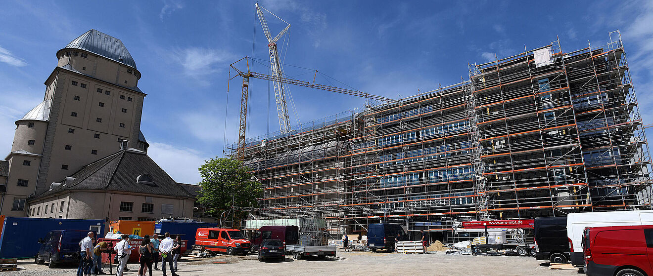 Baustelle des Parkhauses mit Gerüst und zwei Kränen im Hintergrund. Auf der linken Seite befindet sich das Ofenhaus Augsburg.