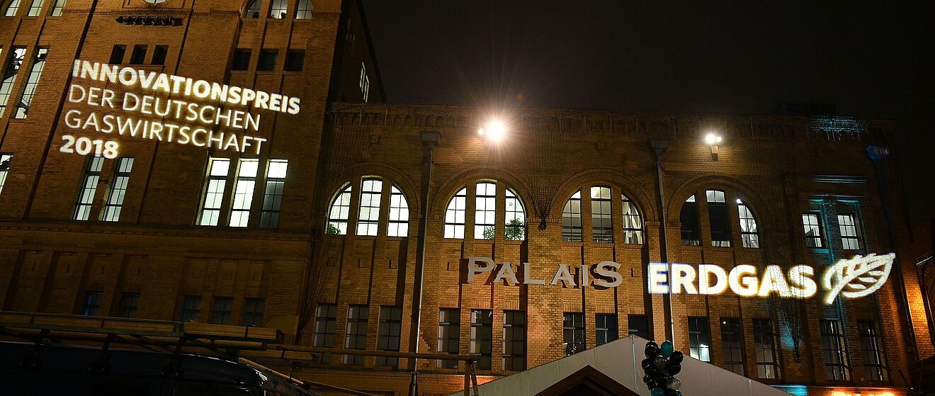 Ein Gebäude bei Nacht mit Projektionen der Aufschriften "Innovationspreis der deutschen Gaswirtschaft 2018" und "Erdgas".