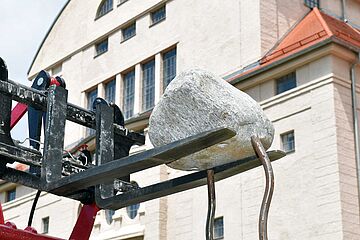 Der Gabelstapler setzt den Stein auf dünnen Eisenstäben ab.