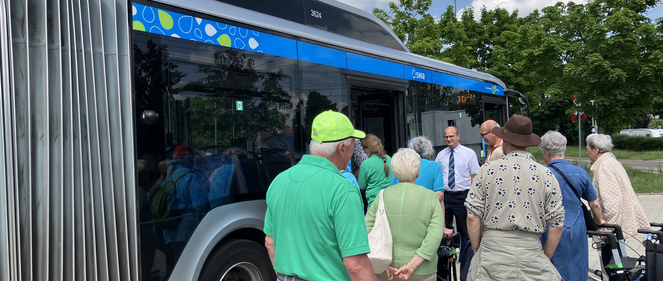 Seniorinnen und Senioren stehen vor einem Bus der swa.