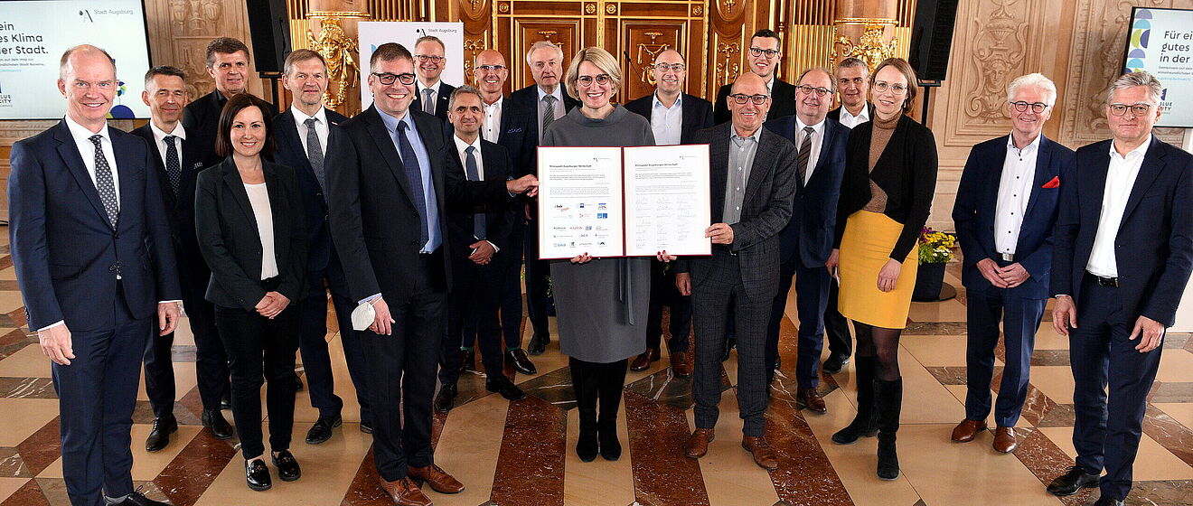 Oberbürgermeisterin Eva Weber hält Zertifikat in der Hand und lächelt. Um sie rum stehen Politiker - Ein Klick auf das Bild führt zur vergrößerten Fotoansicht.