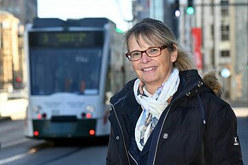 Eine swa Mitarbeiterin lächelt freundlich vor einer Tram. - Ein Klick auf das Bild führt zur vergrößerten Fotoansicht.