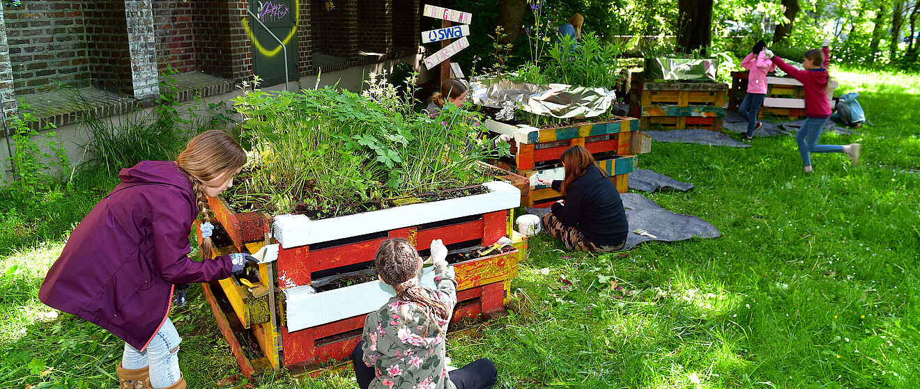 Bild von Kindern, die Hochbeete aus Paletten bunt anmalen