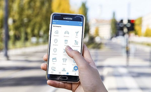 Handy, auf welchem die swa-City App geöffnet ist. Der Hintergrund ist verschwommen.