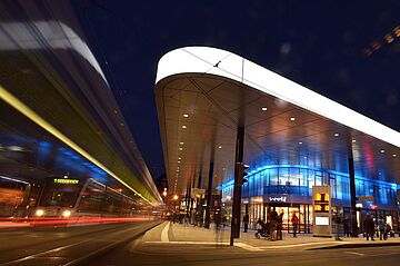 Haltestelle Königsplatz mit einer Straßenbahn bei Nacht.