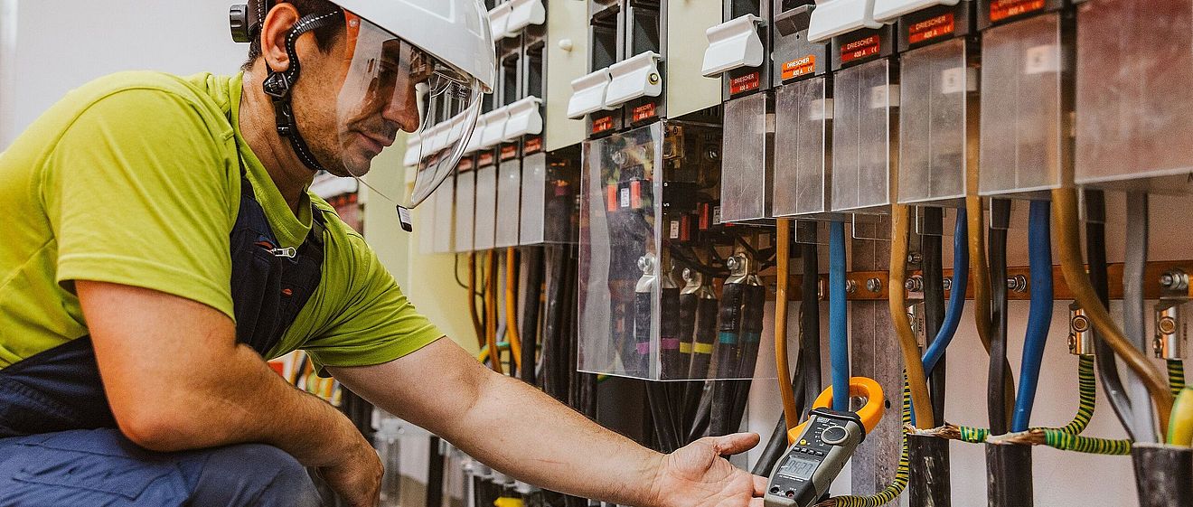 Mann in Schutzkleidung und Helm hantiert an Betriebs- und Automatisierungstechnik