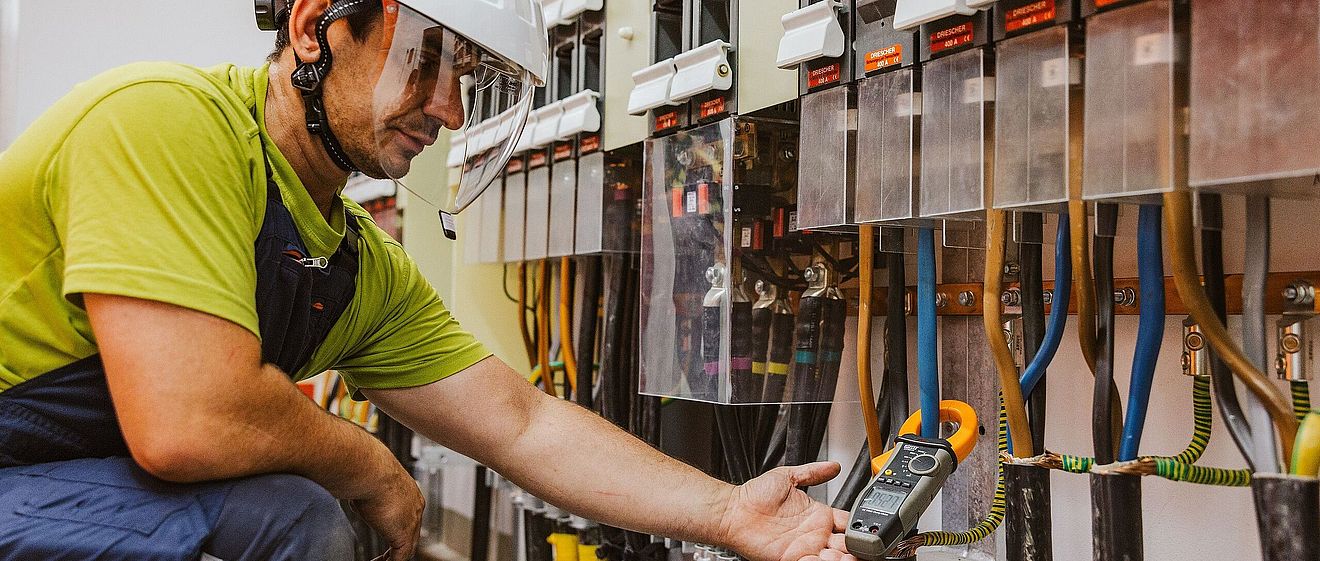 Mann in Schutzkleidung und Helm hantiert an Betriebs- und Automatisierungstechnik