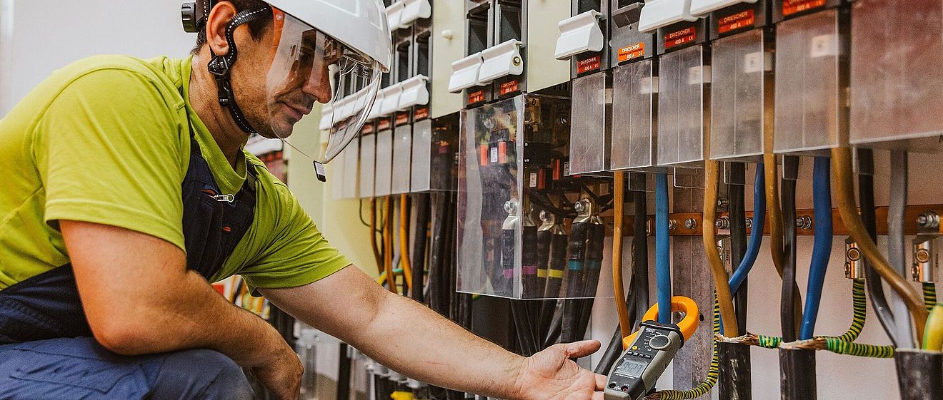 Mann in Schutzkleidung und Helm hantiert an Betriebs- und Automatisierungstechnik