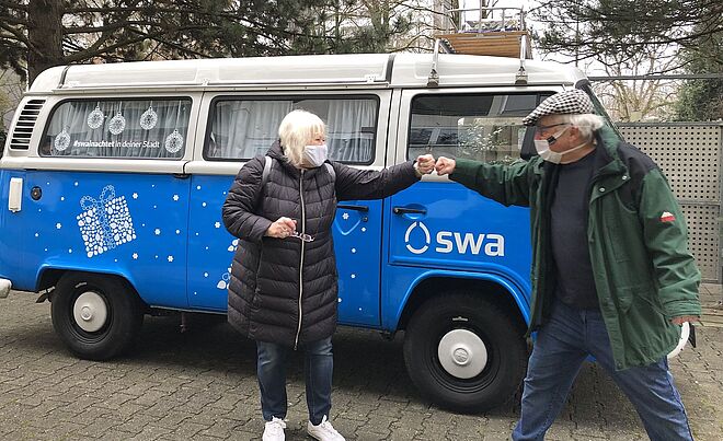 Mann und Frau stehen vor swa-Wasserbulli