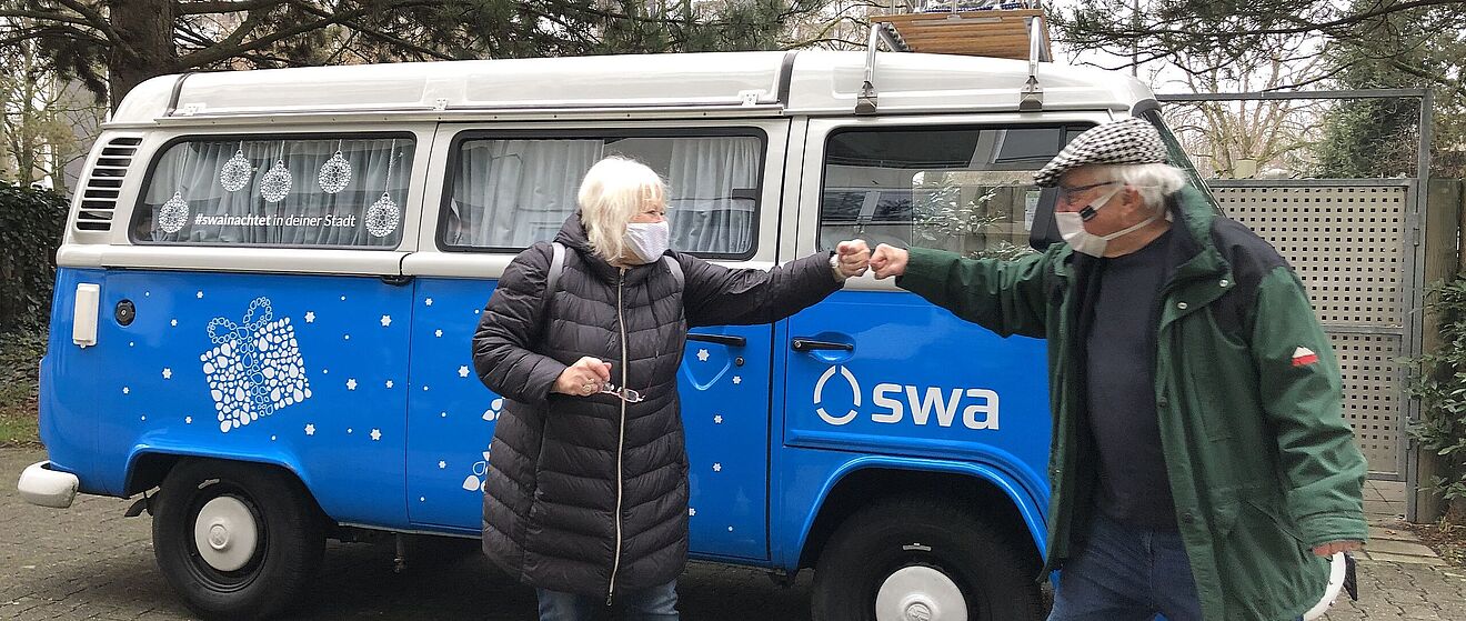Mann und Frau stehen vor swa-Wasserbulli