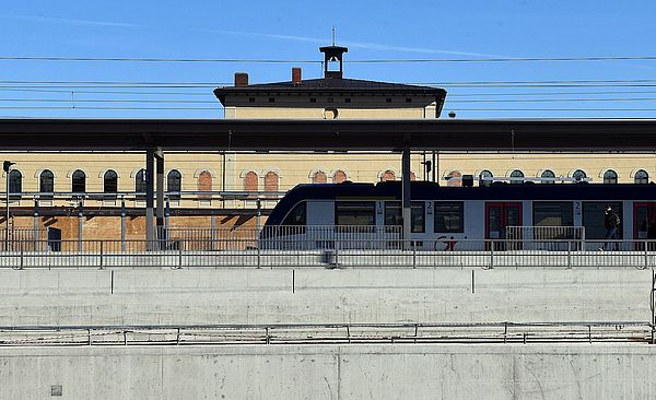 Augsburger Hauptbahnhof. Das Gebäude, ein Bahnsteig und ein Zug sind zu sehen.