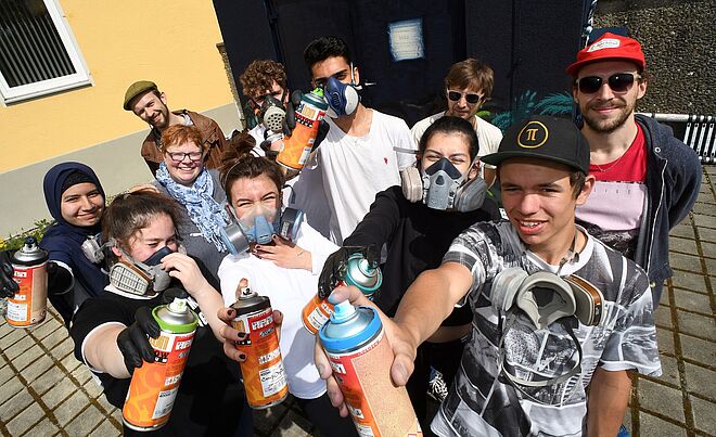 Schüler lächeln und halten Sprühdosen in die Kamera.