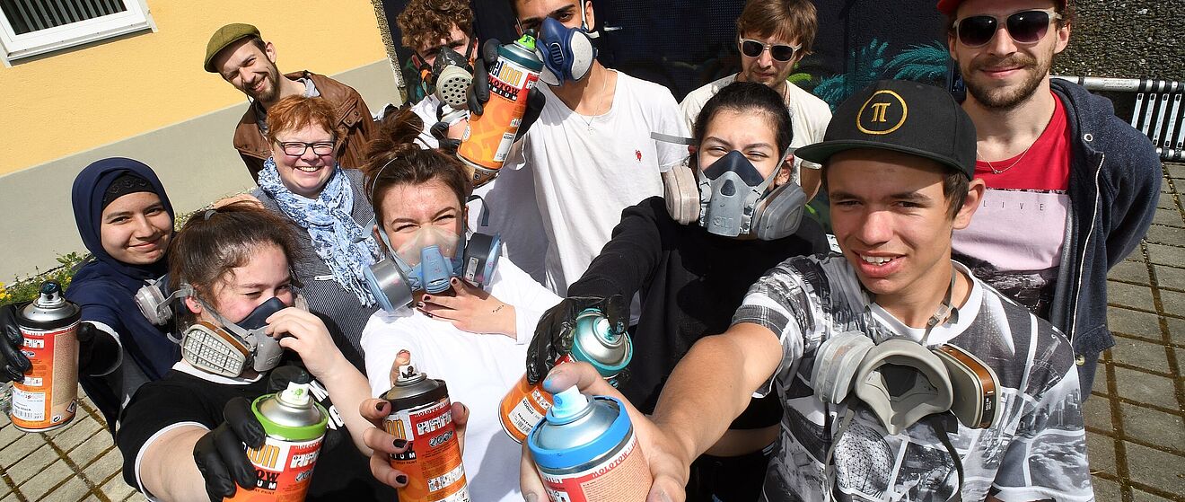 Schüler lächeln und halten Sprühdosen in die Kamera.