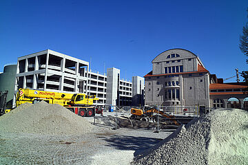 Baustelle mit Kran und Bagger auf dem Gaswerk. Im Hintergrund ist ein Gebäude und ein Parkhaus. - Ein Klick auf das Bild führt zur vergrößerten Fotoansicht.