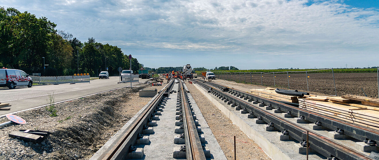 Bau von Straßenbahnschienen neben einer Straße. Link zu einem Pop-Up mit Infos zur Schienenverkehrinfrastruktur