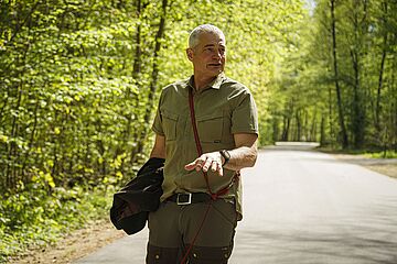 Förster läuft auf einer Straße durch einen Wald. - Ein Klick auf das Bild führt zur vergrößerten Fotoansicht.