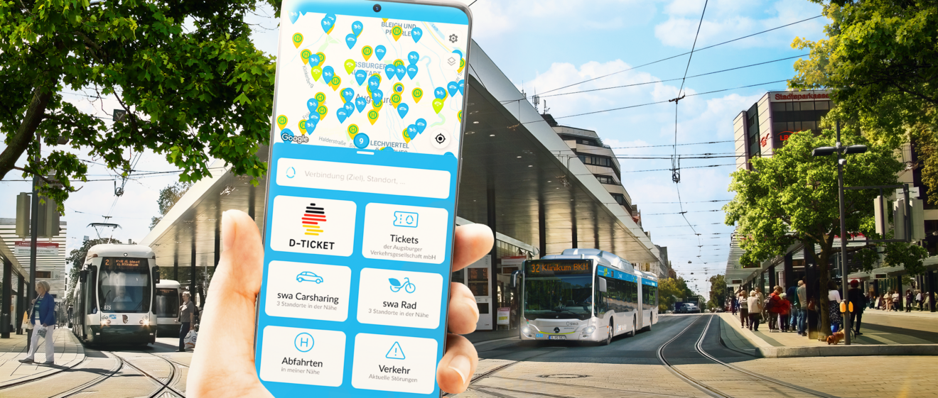 Ein Hand hält ein Smartphone mit der swa Mobil App. Im Hintergrund ist die Augsburger Haltestelle Königsplatz zu sehen.