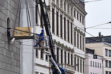 Mann auf einem Personenaufzug und ein Mann im Fenster transportieren eine Box für den Turamichele mit swa Branding. Im Hintergrund ist der Augsburger Rathausplatz
