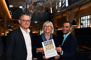 Drei Personen stehen im Ofenhaus und halten eine