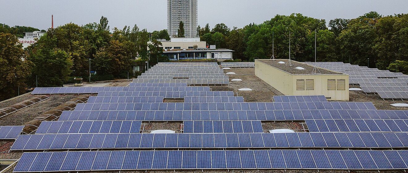 Dach mit Solaranlagen im Hintergrund ist ein Hochhaus.