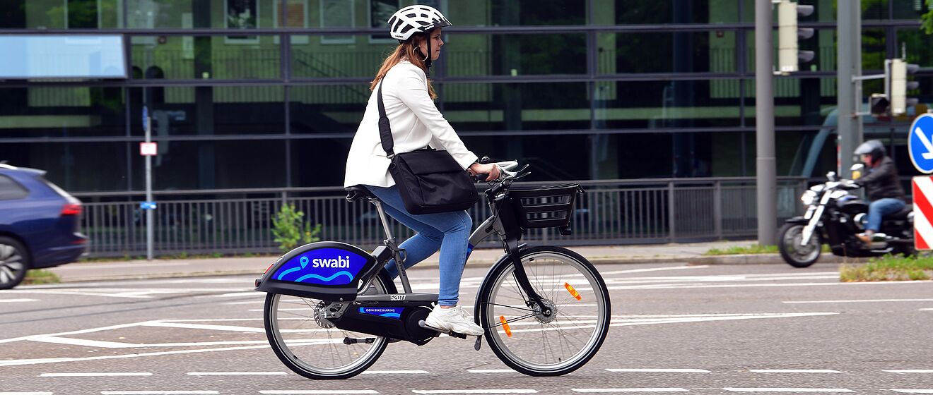 Frau mit Helm fährt auf der Straße mit einem swabi.