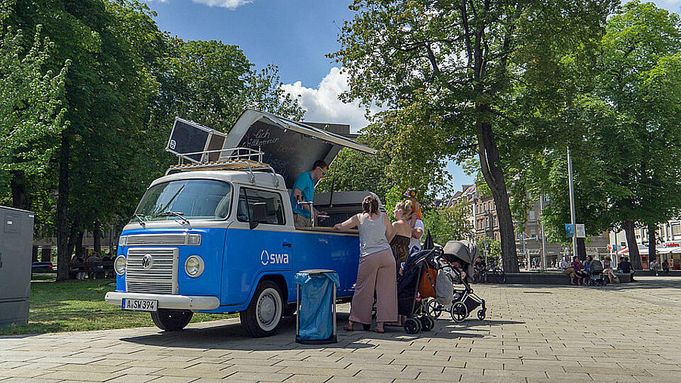 Personen stehen am Bulli und holen sich ein Eis.